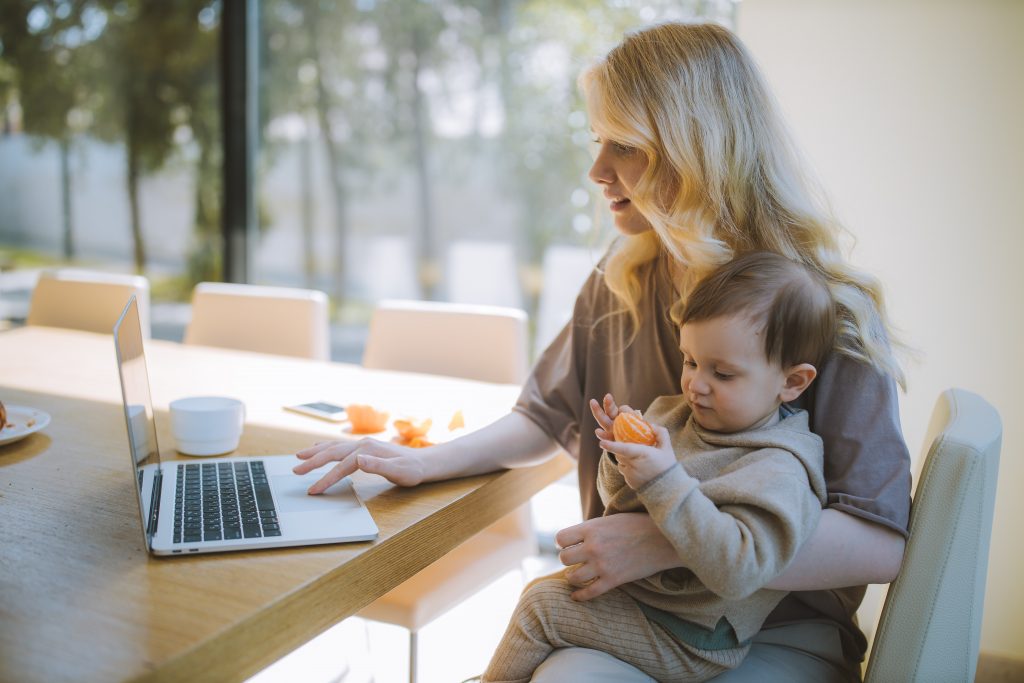 woman carrying her baby and working on a laptop 4079281