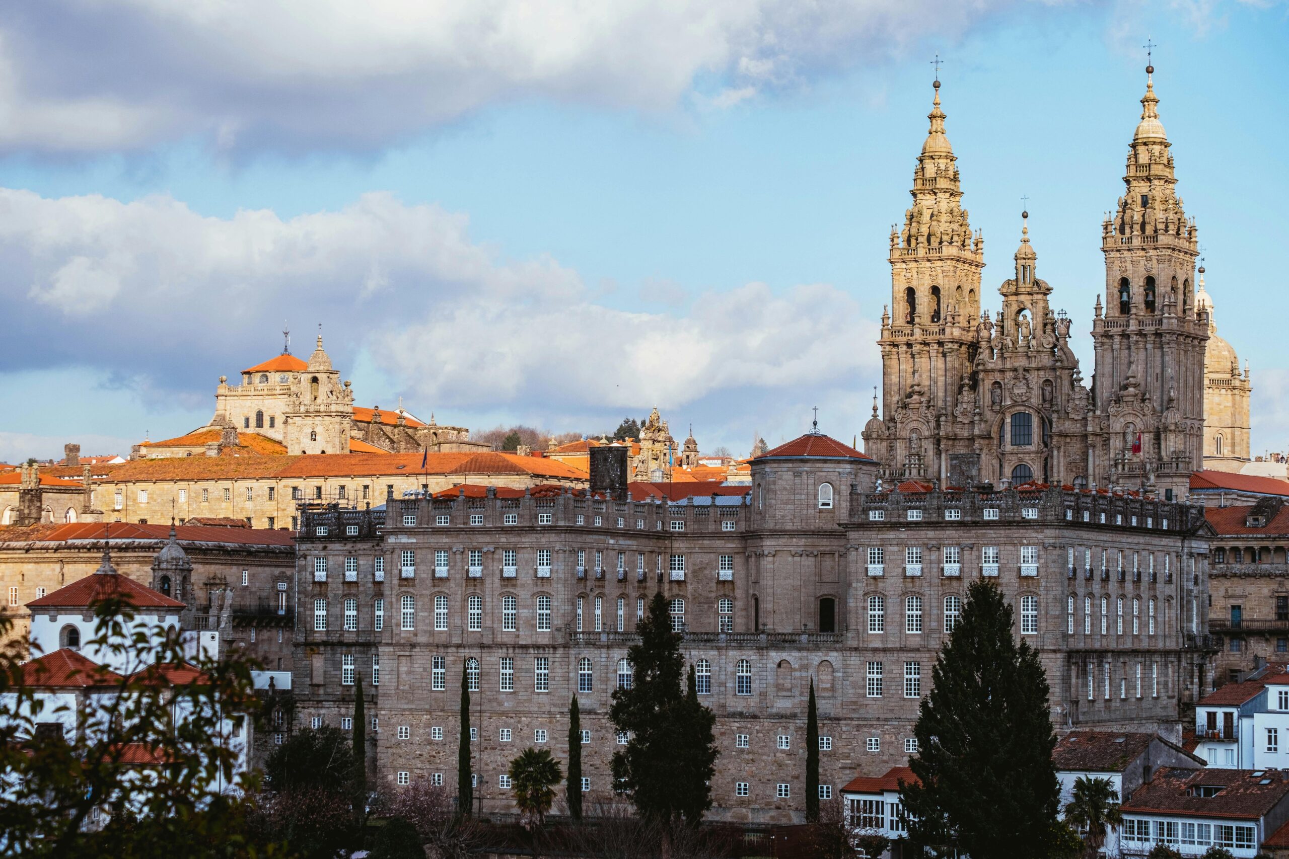 Panoramic view of the historic city of Santiago de Compostela with the ornate Baroque spires of the Cathedral rising above the grand stone buildings.